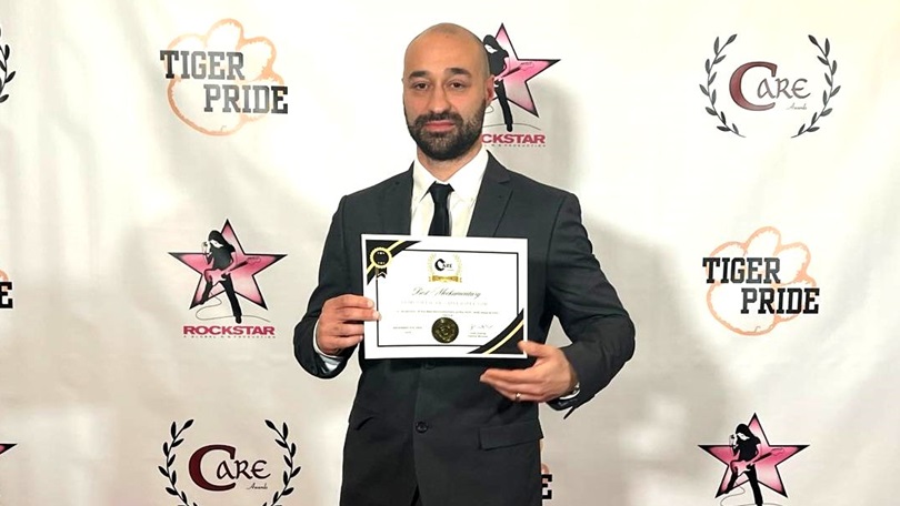 Samuel Lodato holding Best Mockumentary award for 'Remi Milligan: Lost Director' at CARE Awards, standing in front of branded backdrop.