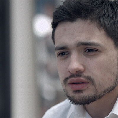 Film still. 3/4 close-up of a stubbly man, looking at something off-screen.