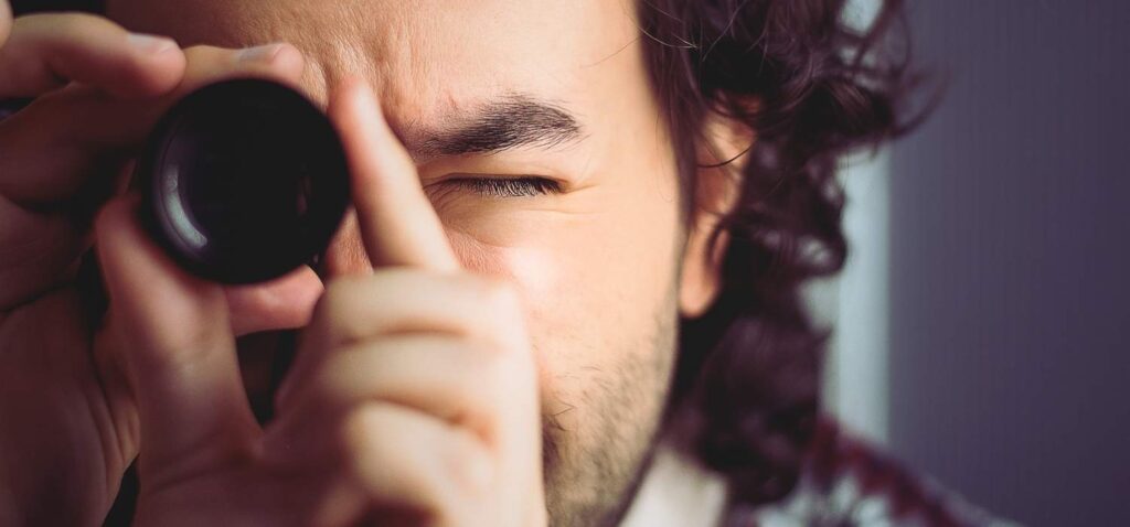Head-on close-up of a man looking into a viewfinder.
